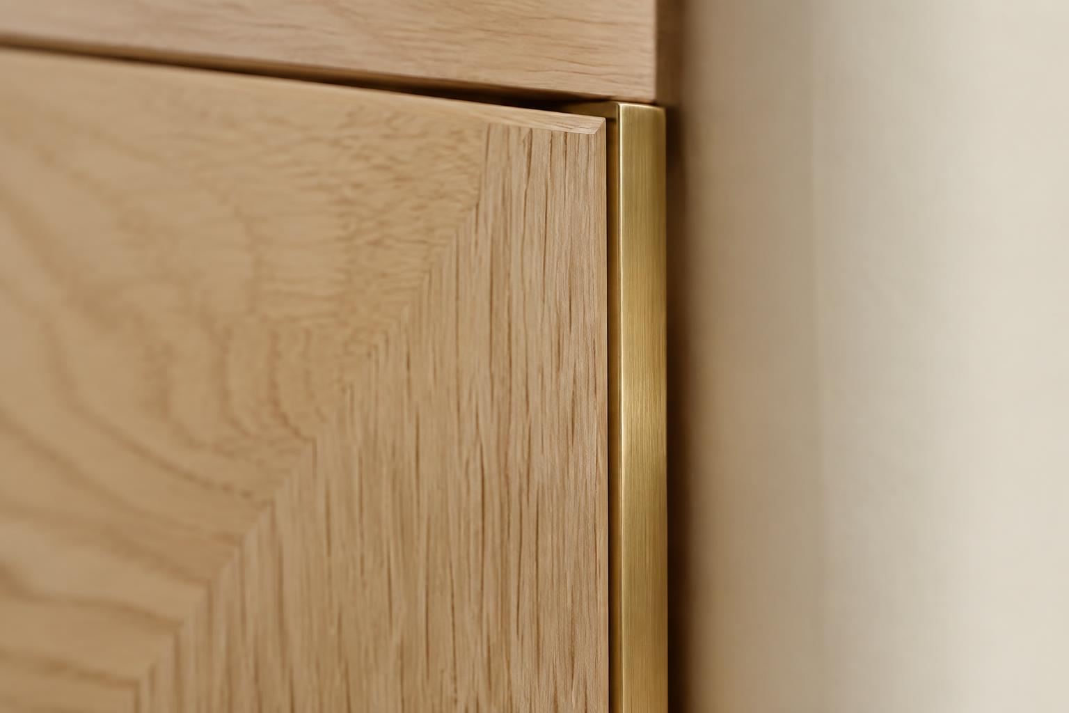 Warm white oak cabinet grain detail with a brushed brass edge